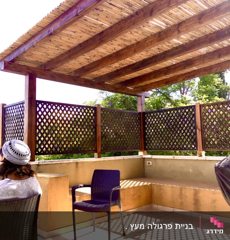 פרגולה מעץ עם גדר עץ מסביב לגינה